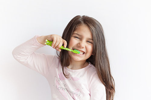 Image Text: 500x332_0045_Little cute child girl brushing her teeth on white background. Space for text. Healthy teeth.